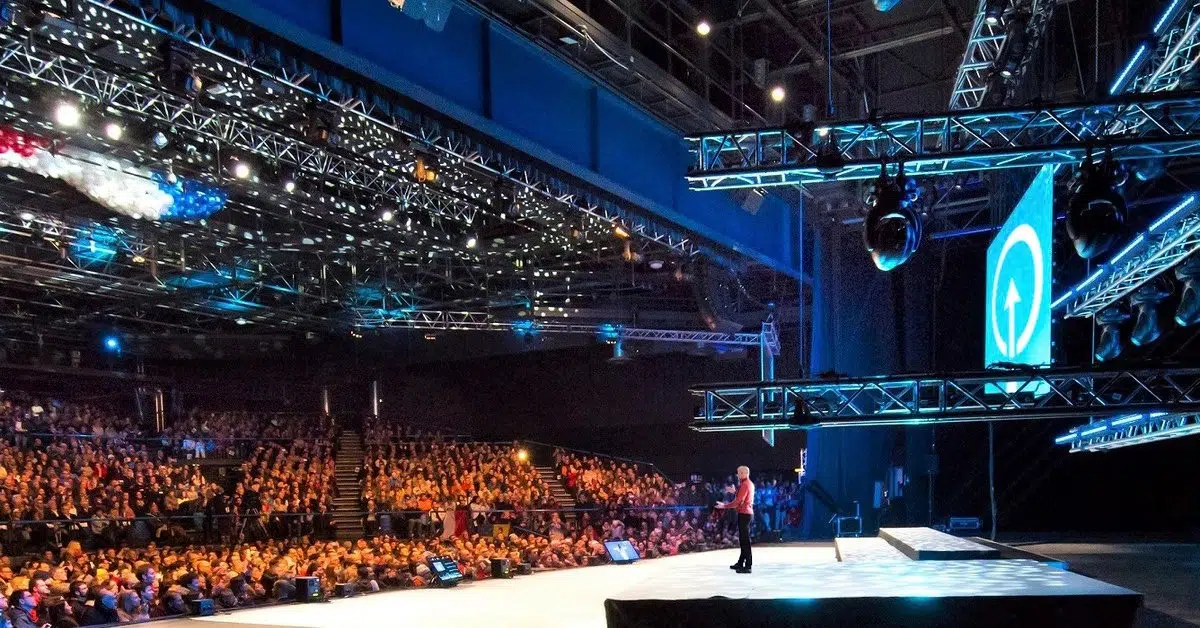 Conférencier sur un grand plateau devant une salle comble lors d’une convention commerciale